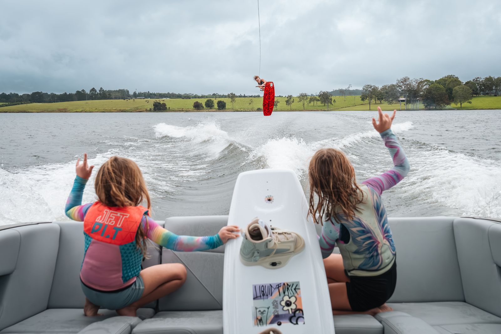 Kids wakeboarding and cheering from the boat